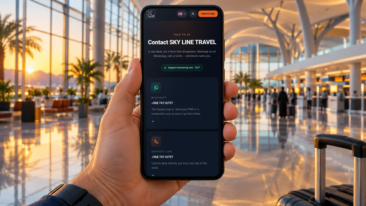 A phone held up in the Muscat airport departures hall, showing the SKY LINE TRAVEL contact page with WhatsApp and phone help